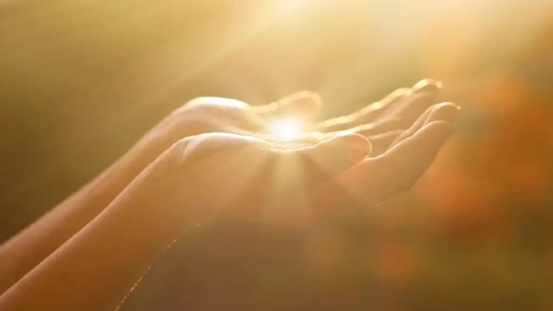 Hands receiving healing light from the sun